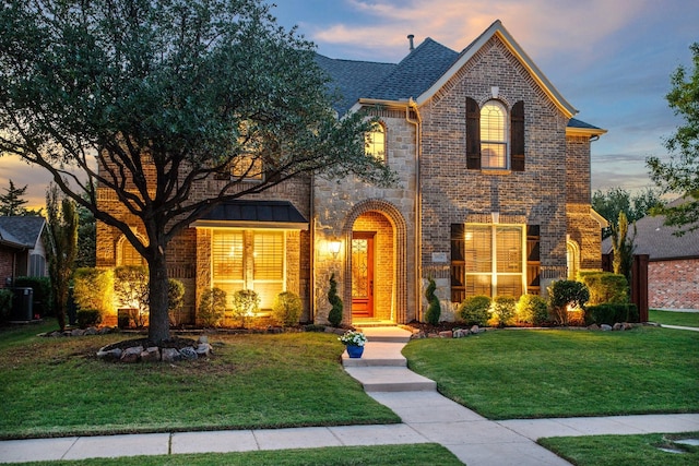 view of front of property featuring brick siding, a front lawn, cooling unit, and stone siding