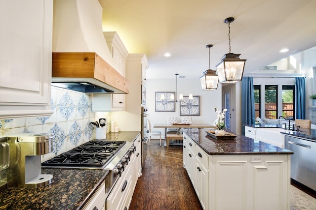 kitchen featuring premium range hood, appliances with stainless steel finishes, a chandelier, dark wood-style floors, and backsplash