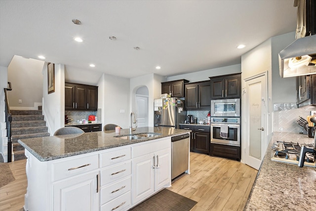 1127 Donnington Trl, Saginaw, TX 76131 - kitchen featuring appliances with stainless steel finishes, a sink, backsplash, arched walkways, and dark brown cabinetry