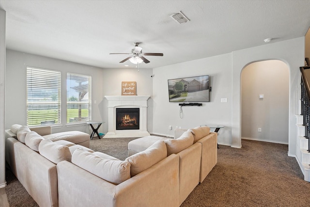 1127 Donnington Trl, Saginaw, TX 76131 - living area with arched walkways, ceiling fan, a glass covered fireplace, baseboards, and dark carpet