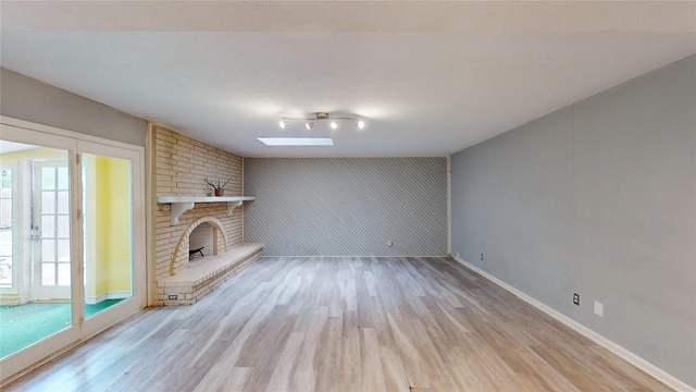 2810 Dove Meadow Dr, Garland, TX 75043 - unfurnished living room with wood finished floors, a skylight, baseboards, and a fireplace
