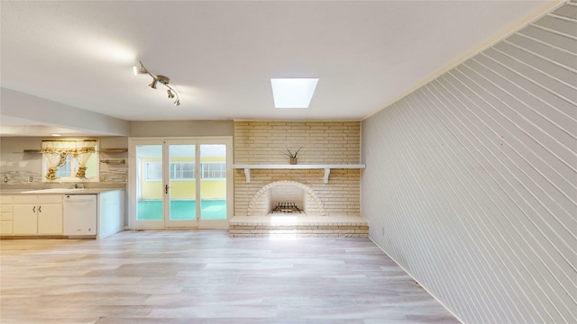 2810 Dove Meadow Dr, Garland, TX 75043 - unfurnished living room with a brick fireplace, a skylight, and light wood-style flooring