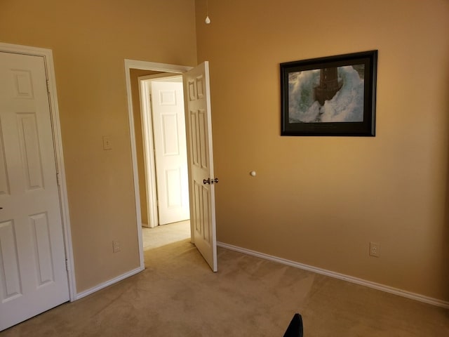 unfurnished bedroom featuring light carpet and baseboards