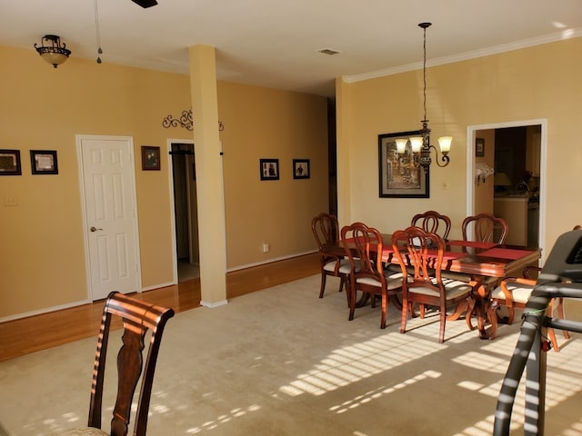 dining area featuring wood finished floors, a chandelier, crown molding, and baseboards