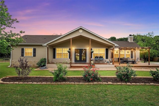 back of property featuring a pergola, a lawn, and a shingled roof