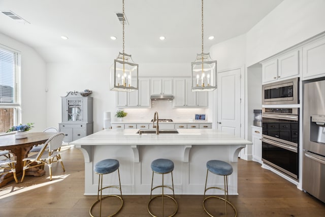 1908 St Andrews Dr, Celina, TX 75009 - kitchen with stainless steel appliances, light countertops, dark wood finished floors, a kitchen bar, and recessed lighting
