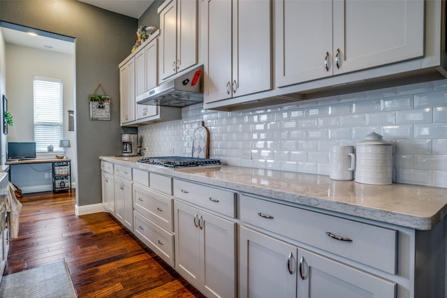 5912 Uplands Dr, Mckinney, TX 75070 - kitchen featuring under cabinet range hood, stainless steel gas stovetop, dark wood-style flooring, baseboards, and decorative backsplash
