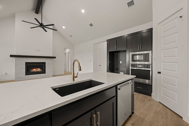 4413 Sandstrom Way, Fort Worth, TX 76179 - kitchen featuring stainless steel appliances, a sink, dark cabinets, beam ceiling, and a high end fireplace