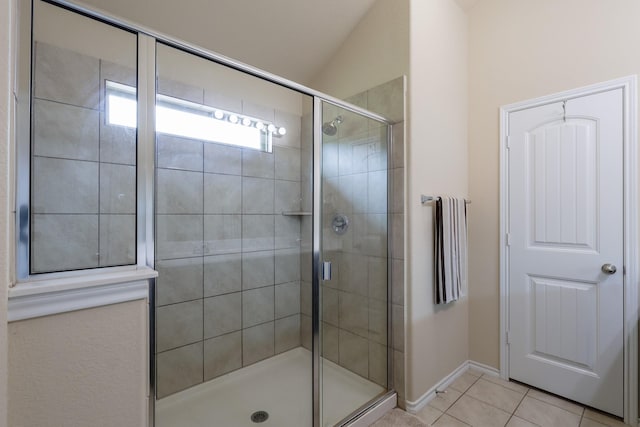 full bathroom with a stall shower, tile patterned floors, baseboards, and lofted ceiling