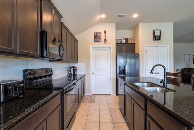 kitchen featuring black appliances, a sink, dark brown cabinets, dark stone counters, and backsplash