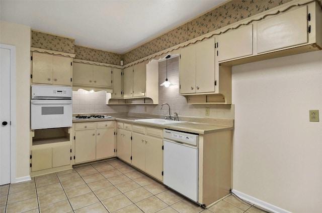 kitchen featuring white appliances, a sink, cream cabinetry, decorative backsplash, and light tile patterned floors