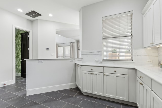 2576 Fountain Cv, Carrollton, TX 75006 - kitchen featuring arched walkways, white cabinetry, light countertops, dark tile patterned flooring, and recessed lighting