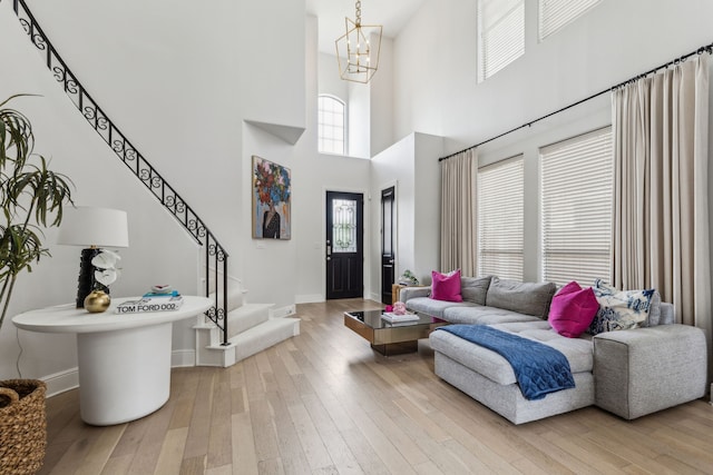 2576 Fountain Cv, Carrollton, TX 75006 - living room with light wood-type flooring, stairway, a chandelier, baseboards, and a towering ceiling