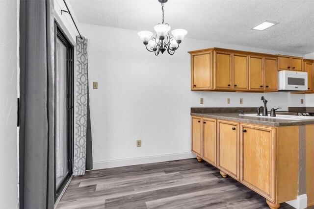 4242 N Capistrano Dr Unit 161, Dallas, TX 75287 - kitchen featuring white microwave, a chandelier, dark countertops, wood finished floors, and a textured ceiling