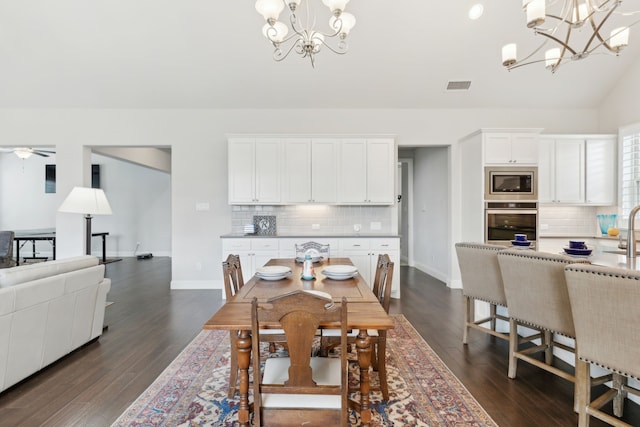 dining space with a chandelier, dark wood-style flooring, vaulted ceiling, and baseboards