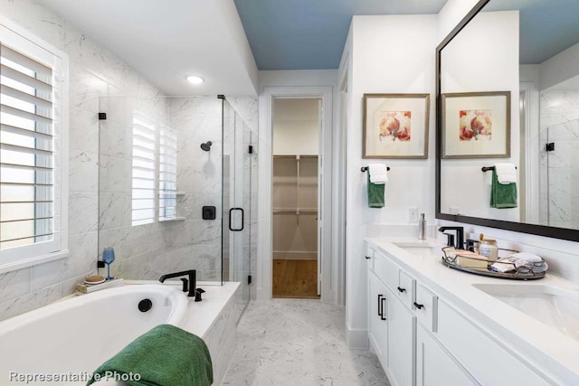 full bathroom featuring a stall shower, a bath, double vanity, and a spacious closet