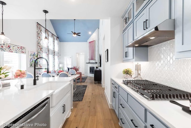kitchen featuring stainless steel appliances, under cabinet range hood, a ceiling fan, high vaulted ceiling, and light countertops