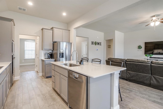 kitchen featuring gray cabinetry, a sink, appliances with stainless steel finishes, open floor plan, and recessed lighting