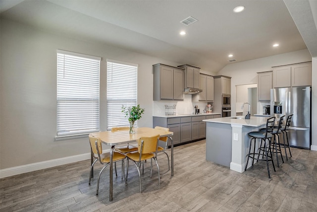 kitchen featuring appliances with stainless steel finishes, gray cabinetry, baseboards, recessed lighting, and vaulted ceiling