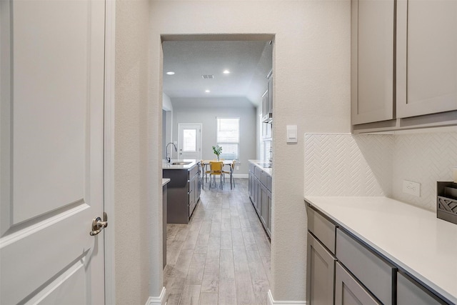 washroom with light wood-style flooring, a sink, recessed lighting, and baseboards