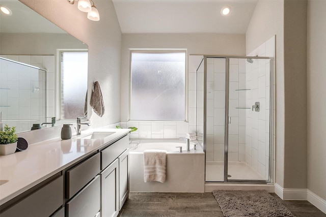 bathroom featuring a shower stall, a garden tub, wood finished floors, double vanity, and recessed lighting