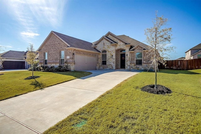 french country home featuring an attached garage, driveway, stone siding, brick siding, and roof with shingles