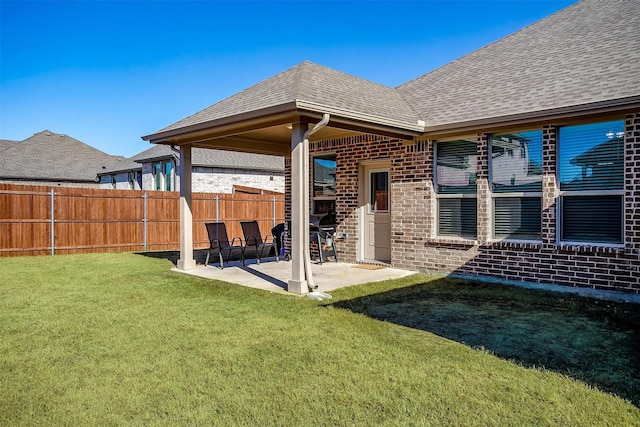 rear view of house with brick siding, roof with shingles, and a patio area
