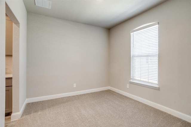 empty room featuring light colored carpet and baseboards