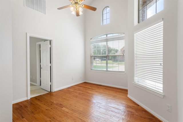 2701 Royal Troon Dr, Plano, TX 75025 - spare room featuring a towering ceiling, light wood-style flooring, ceiling fan, and baseboards