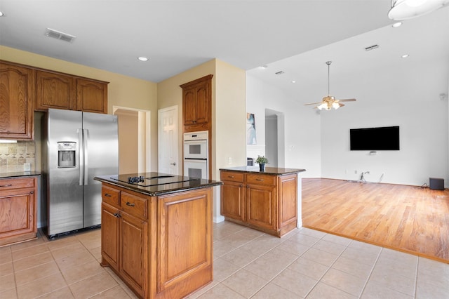 2701 Royal Troon Dr, Plano, TX 75025 - kitchen with stainless steel fridge with ice dispenser, black electric cooktop, double oven, light tile patterned floors, and brown cabinets