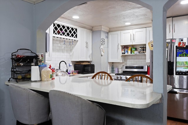 2135 Custer Dr, Dallas, TX 75216 - kitchen featuring appliances with stainless steel finishes, a sink, arched walkways, a peninsula, and white cabinetry