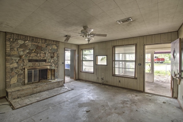 43 Pueblo, Gordonville, TX 76245 - unfurnished living room featuring unfinished concrete flooring, a fireplace, a ceiling fan, and wooden walls