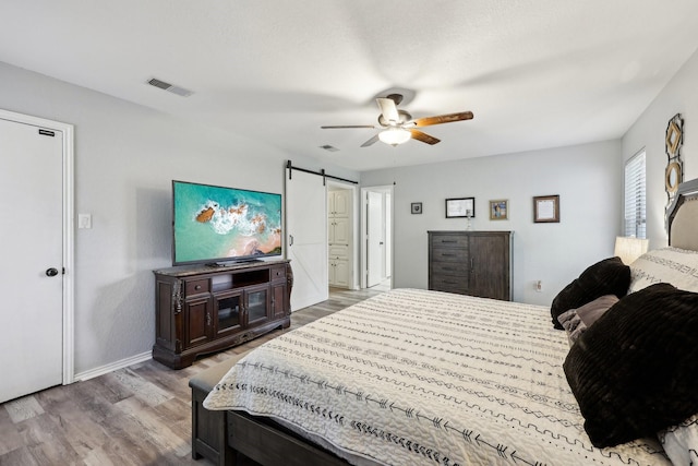 3206 S Fm 51, Decatur, TX 76234 - bedroom with a barn door, wood finished floors, baseboards, and a ceiling fan