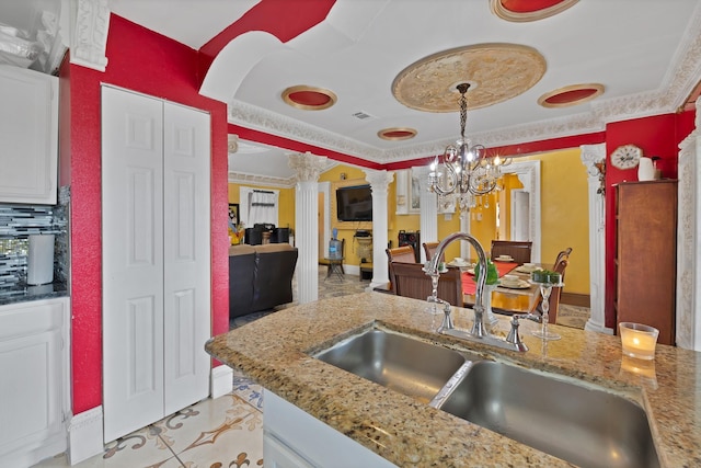 10227 Oak Gate Ln, Dallas, TX 75217 - kitchen featuring decorative columns, a sink, decorative light fixtures, light stone counters, and a raised ceiling