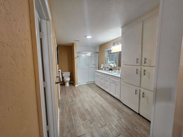 211 Hickory Ln, Weatherford, TX 76086 - full bath with a stall shower, toilet, wood finished floors, vanity, and a textured ceiling