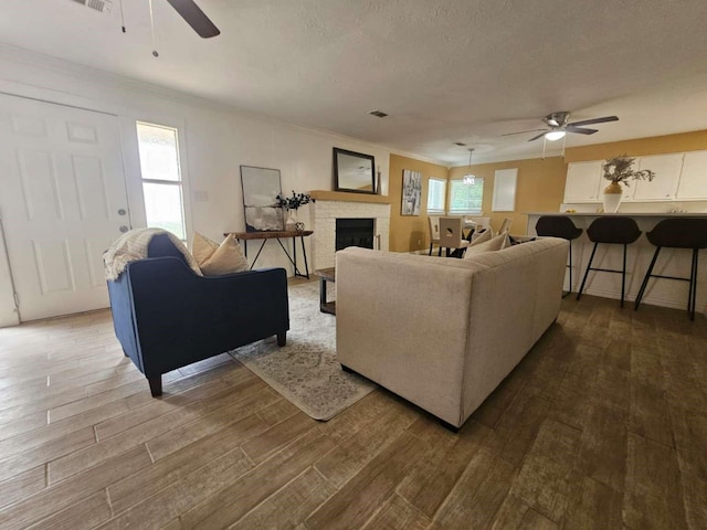 211 Hickory Ln, Weatherford, TX 76086 - living area featuring ceiling fan, dark wood-style flooring, ornamental molding, and a brick fireplace