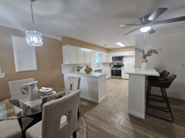 211 Hickory Ln, Weatherford, TX 76086 - kitchen with stainless steel appliances, a peninsula, a ceiling fan, light wood-type flooring, and crown molding