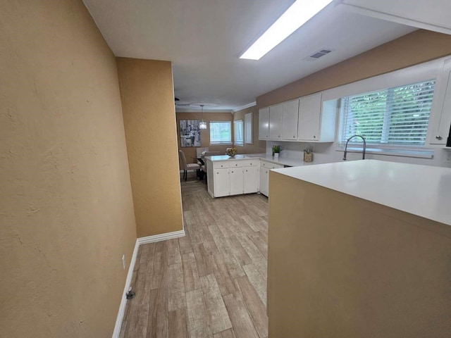 211 Hickory Ln, Weatherford, TX 76086 - kitchen featuring white cabinets, light wood finished floors, light countertops, a textured wall, and baseboards