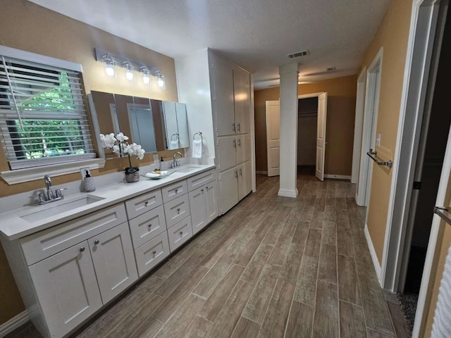 211 Hickory Ln, Weatherford, TX 76086 - bathroom with wood finished floors, ornate columns, double vanity, and baseboards