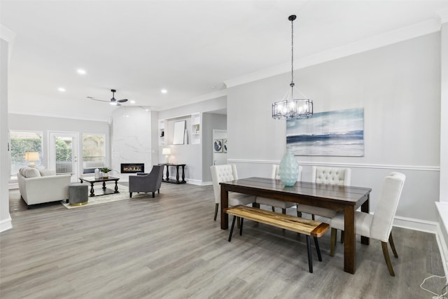 dining space featuring light wood finished floors, a high end fireplace, recessed lighting, crown molding, and ceiling fan