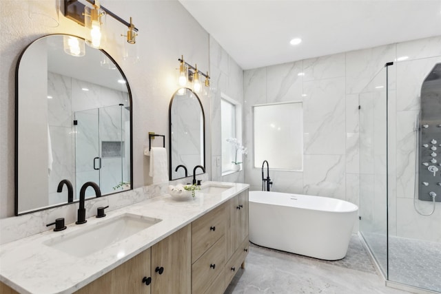 bathroom featuring marble tiled flooring, a marble finish shower, a soaking tub, and double vanity