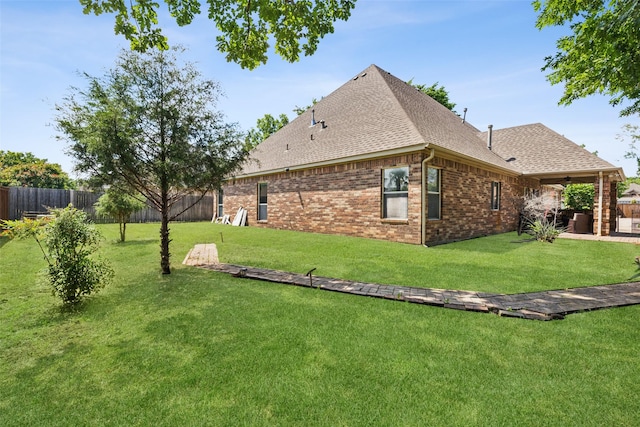 view of side of property with roof with shingles, a ceiling fan, brick siding, and a patio