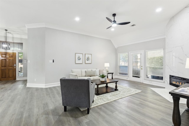 living area featuring ceiling fan, a fireplace, wood finished floors, vaulted ceiling, and baseboards