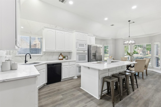kitchen featuring white appliances, a sink, light wood-style flooring, white cabinets, and recessed lighting