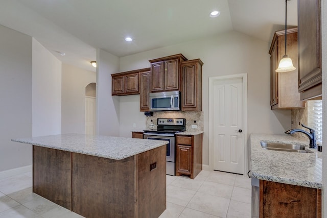 1002 Star Grass Dr, Mansfield, TX 76063 - kitchen with appliances with stainless steel finishes, a sink, arched walkways, tasteful backsplash, and light stone counters