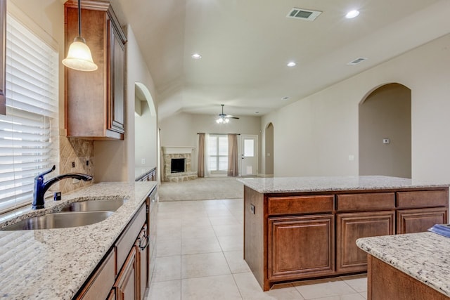 1002 Star Grass Dr, Mansfield, TX 76063 - kitchen with a sink, arched walkways, a stone fireplace, a ceiling fan, and decorative light fixtures