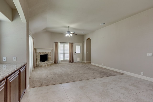 1002 Star Grass Dr, Mansfield, TX 76063 - unfurnished living room featuring light colored carpet, ceiling fan, arched walkways, a fireplace, and light tile patterned floors