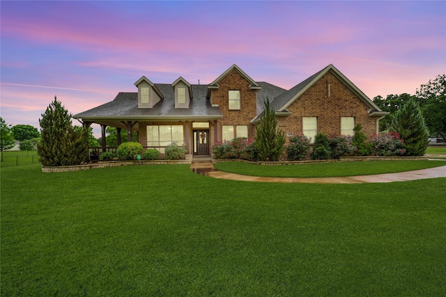 view of front of property with a yard, brick siding, and a shingled roof