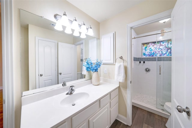 bathroom featuring wood finished floors, a shower stall, vanity, and toilet