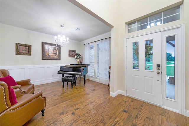 foyer featuring a chandelier, crown molding, wood finished floors, and baseboards